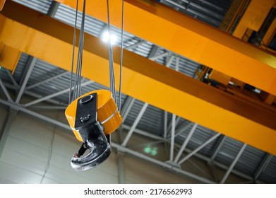 Huge hook assembly of bright yellow moving crane hangs under ceiling in workshop of production plant close low angle shot - Shutterstock ID 2176562993
