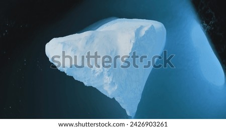 Huge iceberg in blue water aerial top down view. A breathtaking scene of Antarctic big glacier in cold ocean waves. Explore Polar icy wonders. Arctic winter landscape. Panorama drone flight