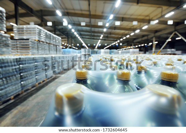 a huge\
industrial warehouse with plastic food wrap wrapped plastic bottles\
with carbonated drinks, water or\
beer.
