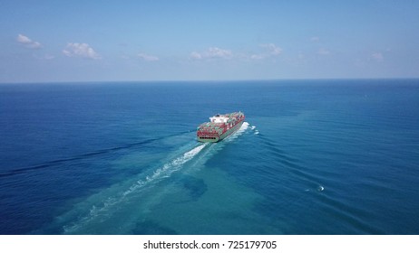 Huge large mega container ship sails on open water fully loaded with containers and cargo - aerial view
