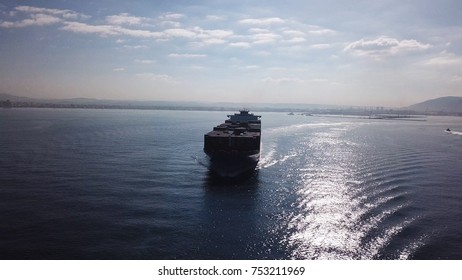 Huge large mega ULCV container ship sails on open water fully loaded with containers and cargo - aerial view