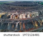 Huge mound of waste rocks. Industrial dump of a mining quarry. Overburden, multi-colored. Evening shot from the air. There may be noise.