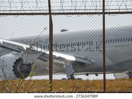 A huge passenger plane pulls onto the runway of Thailand airport, a view through the fence