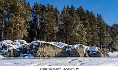 Huge picturesque boulders lie on the bank of a frozen river. A layer of snow on the rocks. Reflection on turquoise ice. Coniferous trees against a clear blue sky. Altai. Katun.  - Shutterstock ID 2206097739