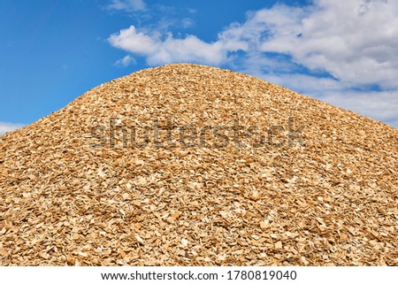 huge pile of fresh woodchips against the sky