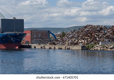 huge pile of rubbish garbage trash with sky background in seaport awaits loading onto dry cargo barge. Waste scrap is stored at quay of cargo seaport, waiting to be melted down to produce new products