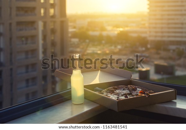 huge pizza in a box with a bottle of mojito on
the sunset city background