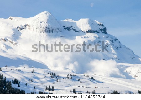 Huge real avalanche in the French Alps with the moon and blue sky