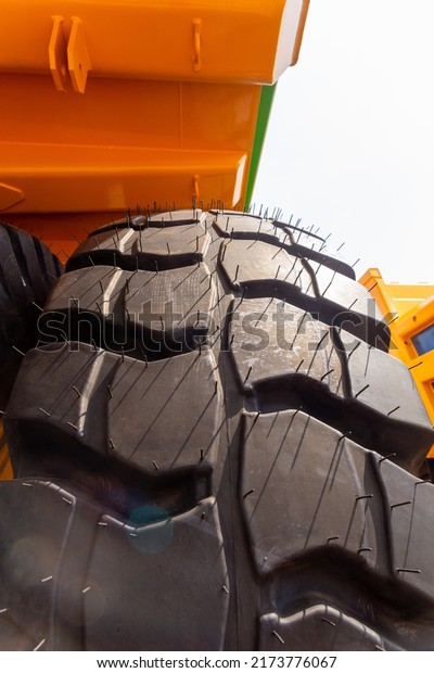 Huge rear wheels of dump truck at unusual angle\
closeup. The wheels have a tread for the movement of the dump truck\
on loose soil.