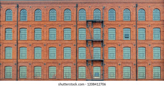 Huge red brick classic industrial building facade with multiple windows and fire escape ladder stairs. Industrial background. Loft inspiration. Construction facade concept. Vintage effect. - Powered by Shutterstock