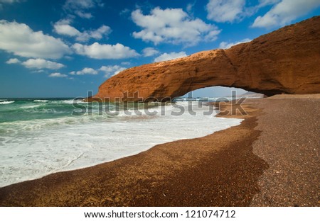 Huge red cliff with arch on the beach Legzira. Morocco