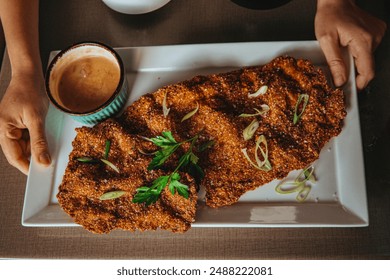 Huge schnitzel in a large plate. Hands holding a plate.