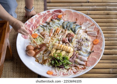 Huge Shabu is a dish made of raw pork and chicken meat, tofu, and a few vegetables. blanch in a pot of hot water. - Shutterstock ID 2253696105