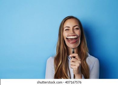 Huge smile through magnifying glass of young woman - Powered by Shutterstock