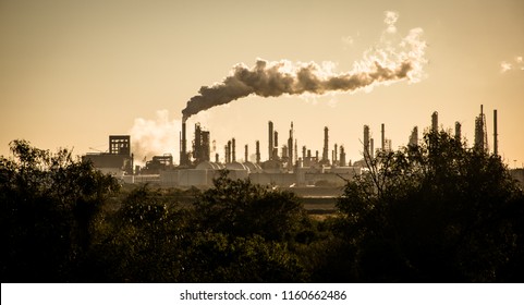 Huge smoke cloud rises from Oil petroleum refinery pollution smoke stack pouring carbon smog into the atmosphere climate change and global warming