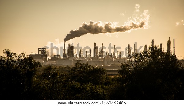 Huge smoke cloud rises from Oil petroleum\
refinery pollution smoke stack pouring carbon smog into the\
atmosphere climate change and global\
warming