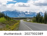 Huge snow capped mountain scene seen outside of Haines Junction, Yukon Territory, Canada with winding road heading to Haines, awe inspiring mountains in spring time.