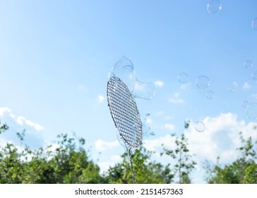 huge soap bubbles in the air against blue sky and green trees. summertime, having fun outside. copy space