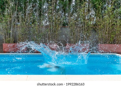 A Huge Splash Of Water Is Created By The Cannonball Dive Into A Swimming Pool