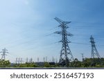 Huge steel electricity towers with power lines and a blue sky in the background.