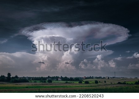 A huge storm cloud with a wall of rain in the countryside.	