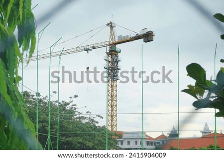 A huge tall crane, used to lift objects horizontally. This machine is equipped with a wire or chain that is driven by many pulleys. Needed for large scale project