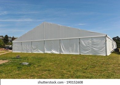 A huge tent in a grass field under sunny sky
