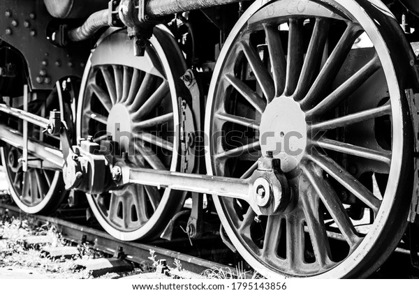 Huge vintage steam locomotive, red painted steel\
wheel detail close up. Coal-powered steam train stands on a siding.\
Classic gigantic heavy railway machinery. Side view of power parts\
of machine.