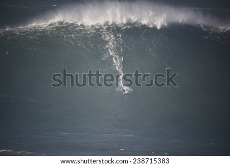 A huge wave breaking with a surfer in Nazare, Portugal. 