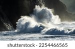 Huge wave crashing against a headland on the south Washington state coast during a king tide