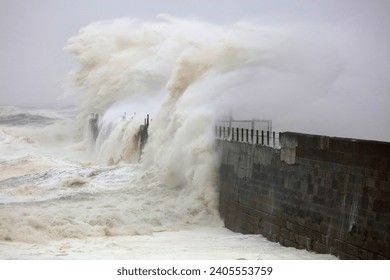 Huge Waves crashing a stone pier during a storm at Hartlepool Headland, County Durham, England, UK.