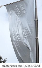 Huge white flag dancing in the wind. Air current blowing and moving the drapery. Fabric gets wrinkles through the movement. Hung high up in Paris, France in a public place. Shot low angle.
