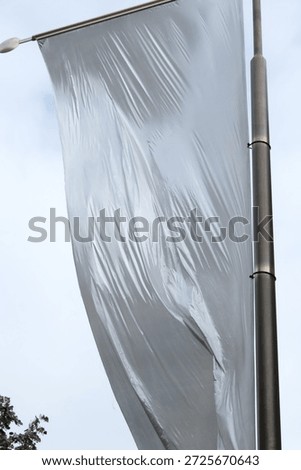 Huge white flag dancing in the wind. Air current blowing and moving the drapery. Fabric gets wrinkles through the movement. Hung high up in Paris, France in a public place. Shot low angle.
