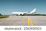 Huge white passenger aircraft accelerating for take-off along the runway, hot exhaust coming out of the engine and distorts the visibility. Side view of two-storey jumbo jet on a ground on a sunny day