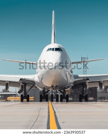 Huge white passenger aircraft taxiing, hot exhaust coming out of the engine and distorts the visibility. Frontal close-up view of two-storey jumbo jet on a ground on a sunny day. 