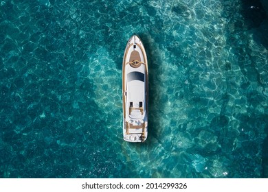 A Huge White Super Mega Yacht On Blue Water In Italy. White Sport Yacht Near The Coast On The Sea Aerial View. Superyacht On Clear Water Near The Rocks, Top View.