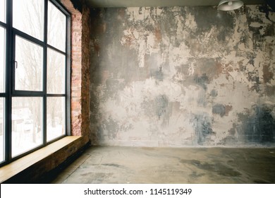 
A huge window to the floor on the entire concrete wall with a wooden window sill. Loft industrial grunge interior. Brick and dark background. Place for text - Powered by Shutterstock