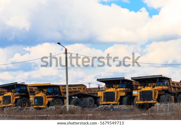 Huge yellow\
dump trucks on a parking near\
quarry