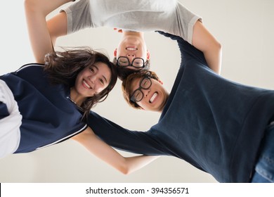 Hugging Asian Friends Standing In Circle And Smiling Ta Camera, View From Below