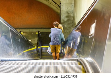 hugging couple going down an escalator to a subway station. - Shutterstock ID 1160314939