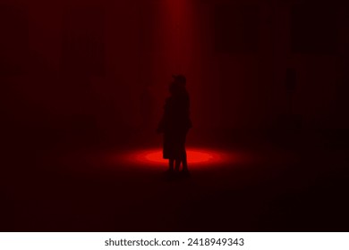 A hugging couple silhouette stand infront of a red backlit spotlight art installation that could be depicted as a club environment or underground warehouse - Powered by Shutterstock