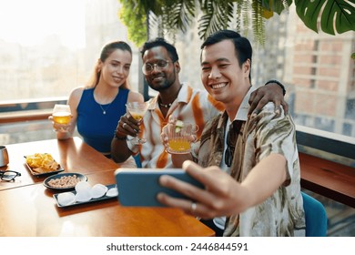 Hugging friends taking selfie when drinking cocktails in rooftop bar - Powered by Shutterstock