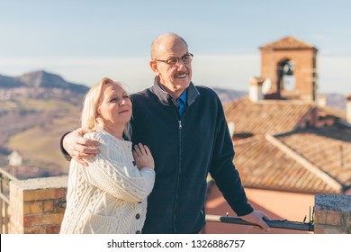 Hugging Senior Couple In Vacation, Visiting Old Italian Town.