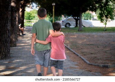 Hugging Young Siblings Walk Together In Public Park. Happy Frindship And Togetherness.