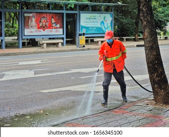 Huizhou, China - FEB 2020: During The Wuhan Pneumonia Outbreak, A Sanitation Worker Wearing A Mask Was Spraying Water To Clean The Road.