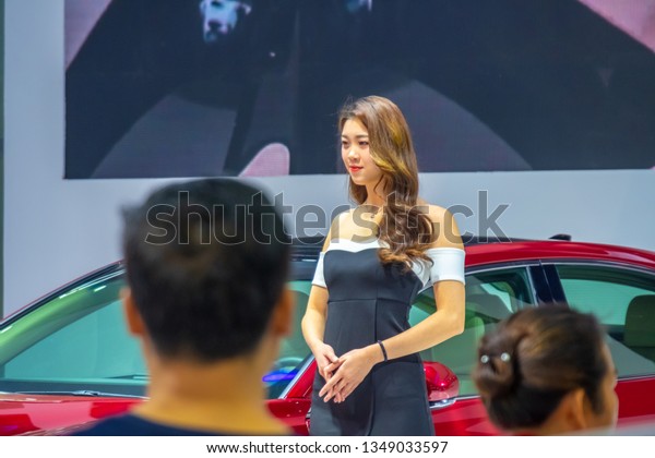Huizhou, China - MAR 2019: Customers &\
salesmen are watching the unidentified female model posed for\
photograph with the new car by Toyota at the Huizhou Broadcasting\
Auto Show in spring