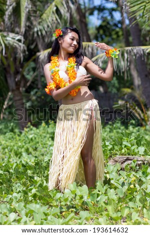 Hula Hawaii dancer in tropical nature. Young woman dancing exotic dance, background palm trees. 