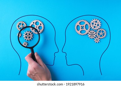 Human brain is made gear mechanism on blue background. The brain is viewed through a magnifying glass. Two different thought processes, concept of different thinking.