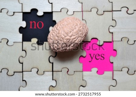 Human brain model placed between puzzle tiles labeled yes and no on vibrant surface symbolizing cognitive choice, mental processing, and decision-making for editorial, educational, and psychology stock photo use