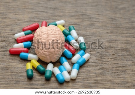 A human brain model surrounded by colorful pills, symbolizing the treatment of neurological and mental health disorders through modern pharmacology.